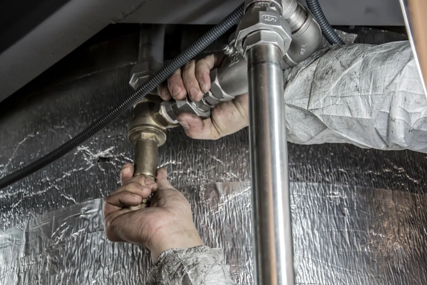 Plumber connecting pipes beneath a kitchen sink