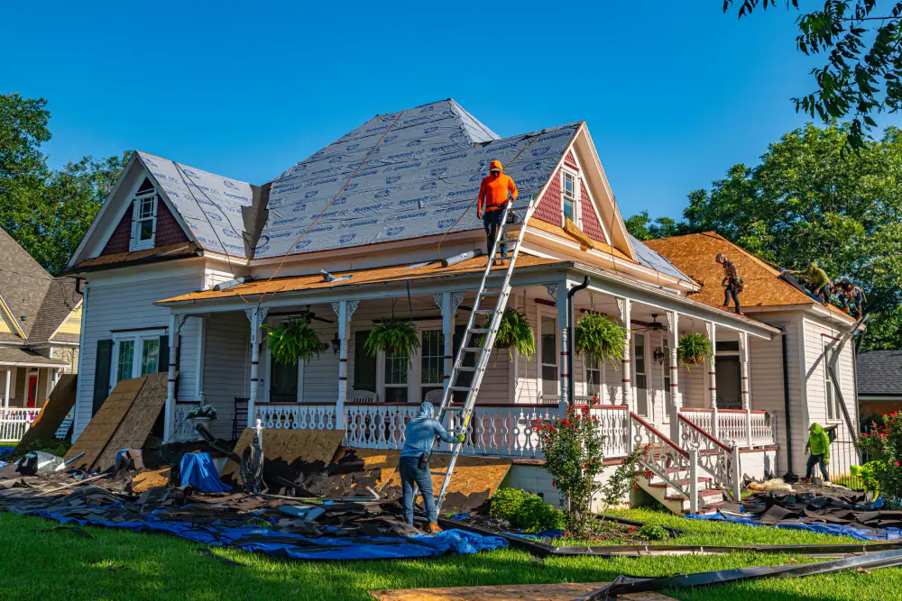Roofers re-roofing a historic home from a ladder
