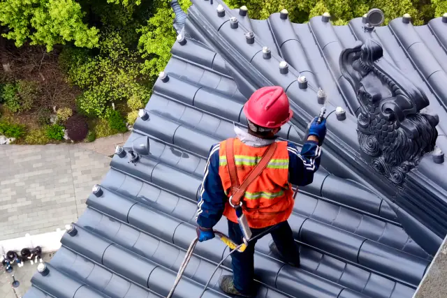 Roofer in safety gear inspecting a roof